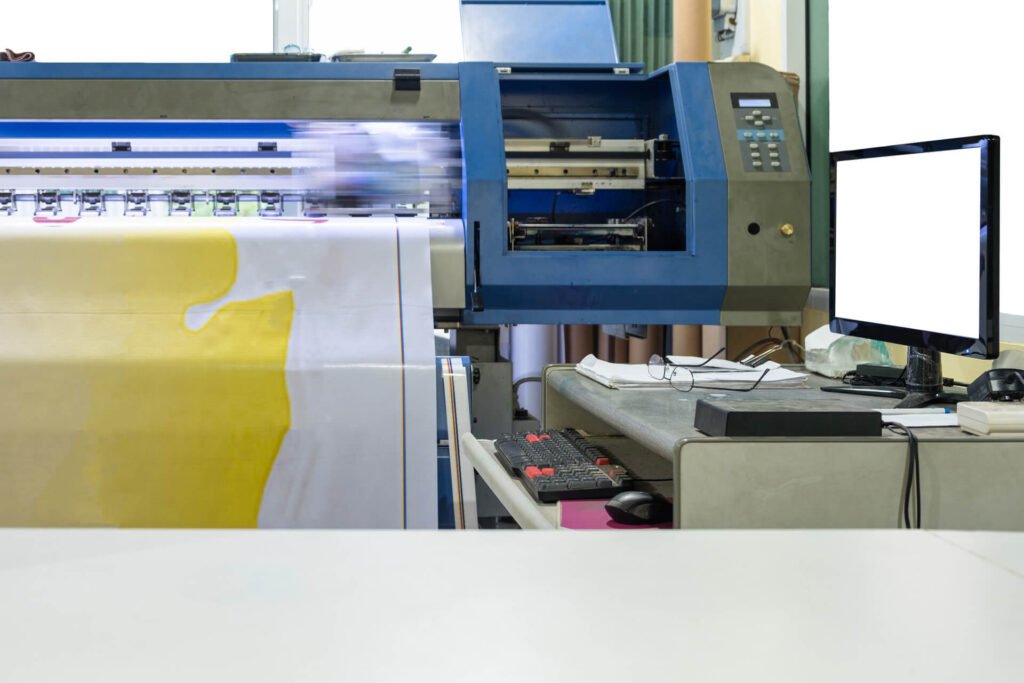 Large inkjet printer working on vinyl banner with computer